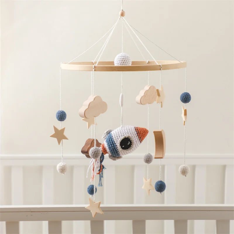 Space-themed baby crib mobile with soft clouds and rocket.